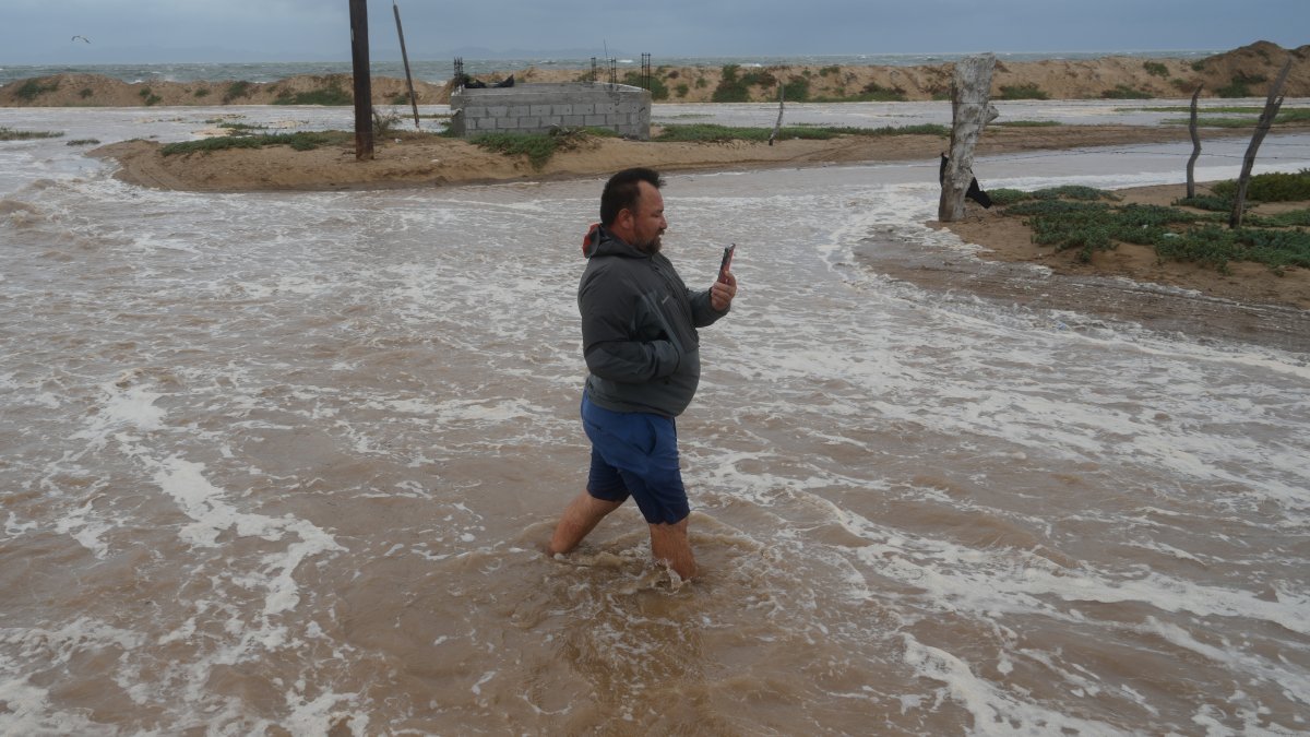 Un hombre camina por una calle junto a la playa mientras avanza por el agua arrastrada por el huracán Polo en Puerto San Carlos, estado de Baja California Sur, México, el lunes 28 de septiembre de 2026. (Foto AP/Eduardo Verdugo)